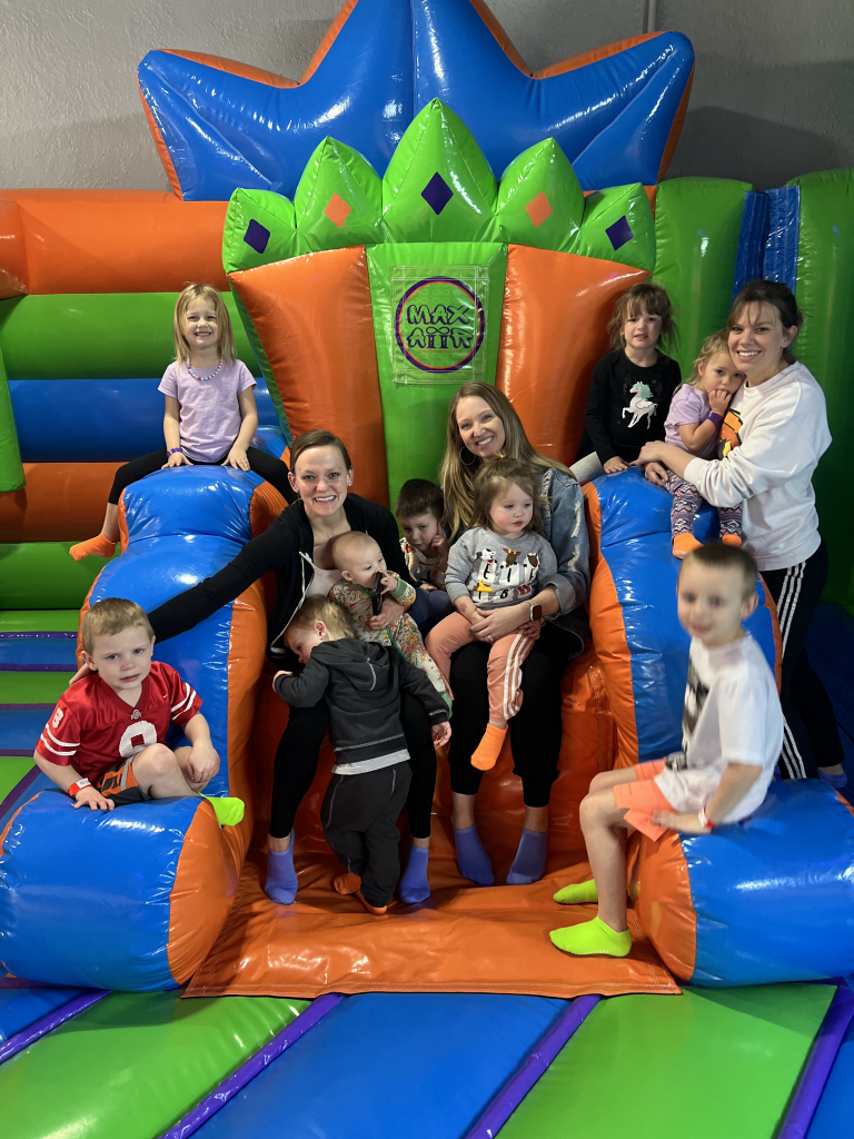 Happy moms and children sitting together on the inflatable throne at MaxAiir inflatapark, smiling and enjoying family time