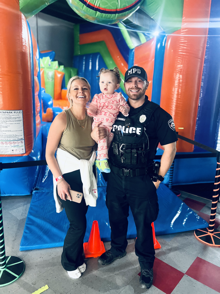 Marion police officer holding his young daughter and standing with his wife at the entrance of MaxAiir inflatapark in Marion, Ohio