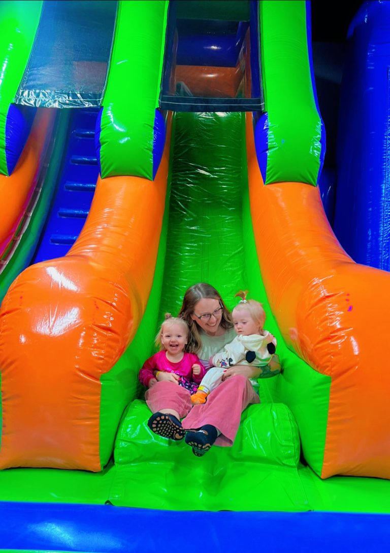 Smiling mom and her children experiencing pure joy as they come down an inflatable slide together at MaxAiir inflatapark in Marion, Ohio