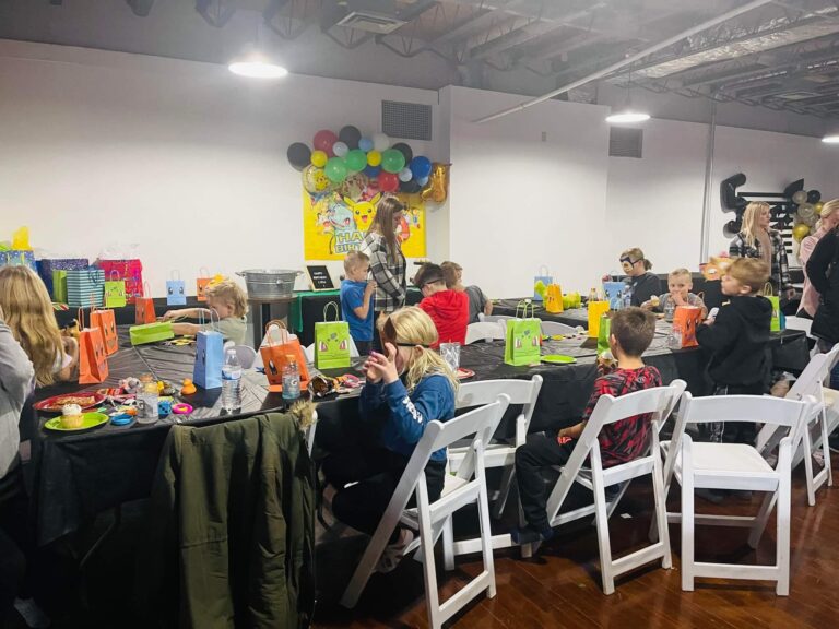 Group of children celebrating a Pokémon themed birthday party with decorated gift bags and cupcakes in MaxAiir’s indoor party bay