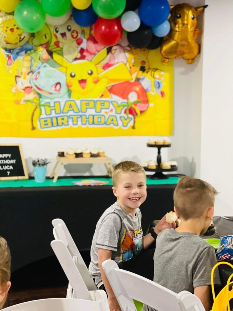 Smiling kids at MaxAiir birthday party with Pokémon decorations, balloons, and dessert table in party rental space