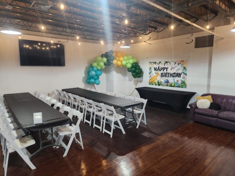 Dinosaur-themed birthday party setup in the Golden Token party bay at MaxAiir with decorated tables, green balloon arch, and Happy Birthday banner
