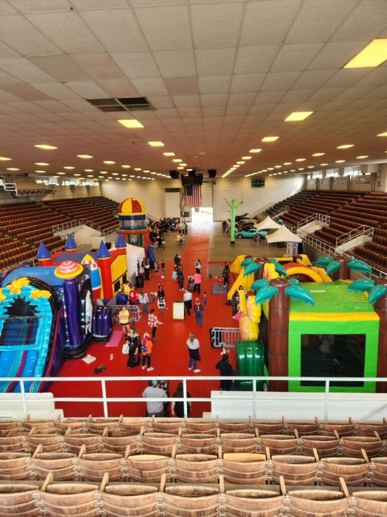 Arena view of Kids and Cars 2024 at Marion Veterans Memorial Coliseum with MaxAiir inflatable slides, bounce houses, and classic car displays